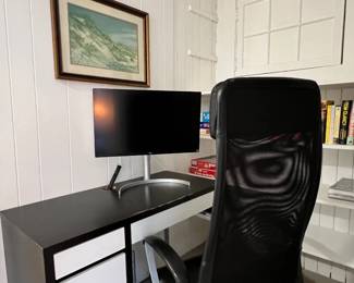 Desk & office chair, monitor, books, artwork.
