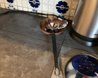Copper Figural Ashtray with Crystal — Small decorative copper ashtray or trinket dish with a floral enamel center and a large faceted crystal accent. The piece shows a warm copper patina and hand-applied blue/white enamel details in the bowl; crystal has no visible chips in photos. Sturdy cast iron handle/stand is attached and shows surface rust consistent with age and use. Compact and decorative for a shelf or table; measurements and condition noted below.