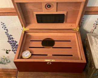 Cedar Wood Humidor Box — Solid cedar humidor box designed to store cigars with a removable slatted tray and built-in hygrometer. The interior shows Spanish cedar lining with ventilation slots and a round hygrometer gauge; exterior is a polished reddish-brown wood with brass hardware and lock plate. Measures roughly to fit on a tabletop and is a mid-size tabletop humidor suitable for 20–50 cigars depending on ring sizes. In good used condition with light surface wear and one small dark mark on the lid; hygrometer and seal not tested and may need calibration.