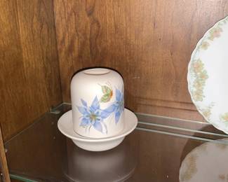 Hand-Painted Floral Ceramic Butter Dish — Charming hand-painted ceramic butter dish with a soft white matte finish decorated with blue floral motifs and green leaves. The set includes a domed cover with a slot-style handle and a shallow matching base, both showing delicate brushwork. Ideal for kitchen or tabletop display; compact size makes it easy to store or include in a dinner setting. In good condition with minor surface wear consistent with light use and no visible chips or cracks.