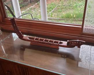 Carved Wooden Canoe Sculpture — Decorative carved wooden canoe with a long slender profile and stylized prow and stern details. Constructed from stained hardwood with cutout seating wells and mounted on a matching wood base, it makes an attractive tabletop accent for a living room or entry. Overall piece measures approximately 30 inches long, 4 inches wide and 6 inches tall, light enough for easy placement but substantial in presence. In good condition with minor surface wear and light finish scuffs consistent with display use.