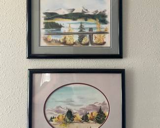 Framed Landscape Watercolor Print — Pair of framed landscape watercolor prints featuring mountain and lake scenes with autumnal trees, each matted and set in simple black frames. The top rectangular piece shows a fence railing overlooking a lake with distant peaks; the lower piece is a circular-matted landscape with soft pastel skies. Both frames appear lightweight with glass, suitable for casual wall display; some light wear and age visible on mats and frames from normal hanging. Overall an attractive decorative pair that are ready to hang together or separately; see dimensions for each frame.