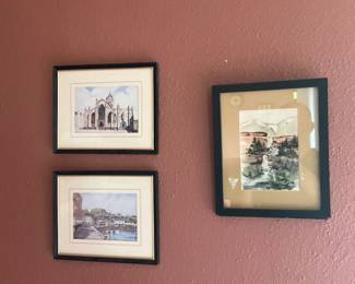 Three Framed Watercolor Prints — Group of three small framed watercolor prints featuring architectural and landscape scenes in simple black frames with gold inner trim and double mats. Each print appears to be a reproduction rather than original watercolor and shows typical display wear: small scuffs to frames, mat discoloration, and glass reflections visible. Frames are lightweight and ready to hang as a coordinated gallery grouping in a hallway or living area; see dimensions for approximate sizes.