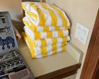 Yellow White Striped Bath Towels — A stack of four yellow-and-white striped bath towels in soft, absorbent terry cotton shown folded. Bright alternating stripes are visually striking and suitable for guest bathroom or pool use; towels appear lightly used with no visible stains or holes. Each towel is a standard bath size and colorfast looks intact from photos. Good everyday condition and easy to fold into linen storage.