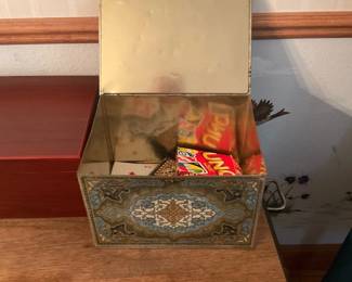 Decorative Metal Storage Tin Box — Decorative hinged metal storage tin featuring ornate floral/medallion printing in blue, gold and cream tones. Rectangular box with hinged lid and side bail-style handles, lined with reflective metal interior suitable for storing household items or games. Approximate overall size and weight make it an easy tabletop or shelf accent for entryways or living rooms. Shows light surface wear, patina and minor dents consistent with age but no holes or major damage.