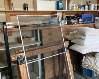 Aluminum Frame Window Storm Panel — Aluminum-framed window storm/screen panel suitable for a single large window opening. The panel features a clear glass or plexiglass upper section and a mesh or dark lower section within a silver aluminum frame; mounting clips are attached at the sides. Overall dimensions are estimated to fit a tall single-hung window and the lightweight aluminum construction makes it easy to handle. Condition is good with minor surface wear to the frame and no obvious cracks in glazing or mesh visible in photos. Sold as-is for home repair or replacement; buyer should verify exact fit and whether glazing is glass or acrylic before installation.