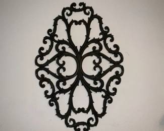 Ornate Iron Wall Plaque — Decorative ornate iron wall plaque with an openwork scroll and foliate motif in a dark finish. The lightweight cast-iron or pressed-metal piece is meant for vertical display and brings a traditional, decorative accent to hallways or living spaces. Solid condition with typical surface wear and a few small scuffs to the finish visible in photos; no breaks or missing sections noted. Measures modestly and is easy to hang with a single wall hook or small nail.