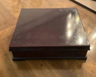 Wood Jewelry or Keepsake Box — Simple square wooden keepsake or jewelry box with a dark brown polished finish and stepped base. The box appears to be solid wood or wood veneer with a hinged lid (hinges not visible in photos) and shows light surface scratches and wear consistent with normal use. Approximately palm-sized and easy to tuck on a dresser or shelf for jewelry, photos, or small valuables. In good functional condition with cosmetic surface wear; hinges and interior not shown so sold as-is.
