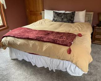 Queen Bed with Carved Wood Headboard — Solid-looking bed setup featuring a carved rectangular wooden headboard with geometric trim and painted distressed finish, shown with neutral duvet, white bedskirt and decorative pillows. The headboard adds a subtle folk or farmhouse character and appears to be separate from the mattress so it can be reused on other frames. Bedding shows normal household use with light wrinkling and no obvious stains; headboard finish has minor wear consistent with age. Overall a practical queen-size bedroom set element suitable for immediate use or redecoration.
