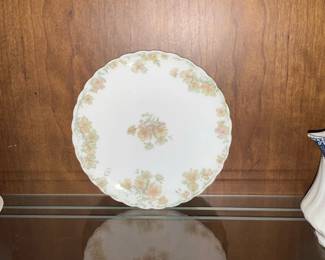 Floral Scalloped Porcelain Dinner Plate — Delicate porcelain dinner plate with scalloped edges and a soft floral spray pattern around the rim and center. The white ground is decorated with yellow and peach roses and green foliage, and the rim has a subtle gold trim. Plate measures approximately 10.5 inches in diameter and is lightweight but sturdy for display or occasional use. Good estate condition with light surface wear and no visible chips or cracks from photos.