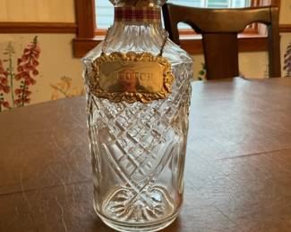 Cut Glass Scotch Decanter with Label — Decorative cut glass decanter labeled "SCOTCH" with a matching stopper and an ornate brass/metal hanging label. The bottle features deep cut-glass diamond and fan patterns typical of pressed or cut crystal barware and measures as a tabletop spirit decanter. Measuring approximately 11 inches tall with a 3.5 inch diameter base, it holds a standard decanter volume and is easy to display on a bar or in a cabinet. In good vintage condition with no obvious chips or cracks visible from photos; the metal label shows light tarnish consistent with age.