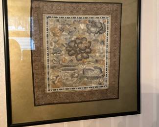 Framed Embroidered Textile Panel — Framed embroidered textile panel featuring a central floral motif with metallic gold accents and layered decorative borders. The piece is double-matted and set in a thin black wood frame with glass, making it ready to hang. Overall framed dimensions are estimated to fit standard wall art and it's lightweight enough for a single-stud hanging; the textile portion shows detailed stitching and a muted neutral color palette. In good condition with intact glass and frame; the textile shows slight age-related toning but no visible rips or stains.