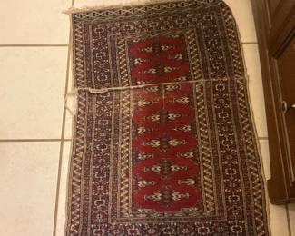 Red Geometric Wool Runner Rug — Handwoven-style runner with traditional geometric motifs and a red field framed by multiple patterned borders. The rug shows visible wear: frayed fringe, some edge wear, and a split seam down the center that is visible in photos; pile appears low but colors remain warm. Lightweight and narrow, it works well as a hallway or kitchen runner; construction appears wool-on-cotton foundation typical of small oriental runners. Measurements are approximate and priced for condition.