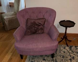 Button-Back Pink Accent Chair — Upholstered button-back accent chair in a muted pink/lavender fabric with nailhead trim along the arms and tapered dark wood legs. The wing-style back with tufted buttons and included plush throw pillow make it a comfortable occasional chair for a living room or bedroom. Shows light, even wear consistent with normal use; fabric appears intact with no visible rips or stains in photos. Compact footprint works well in smaller rooms — see dimensions for sizing.