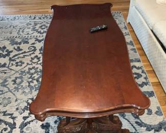 Carved Mahogany Coffee Table — Solid carved mahogany coffee table with a scrolled rectangular top and decorative pedestal base. The top shows light surface wear and a few small scratches consistent with normal use; base carving remains crisp and sturdy. Traditional styling works well with classic or transitional living rooms and the lower stretcher adds stability. Overall solid condition and ready for use; see photos for surface blemishes.