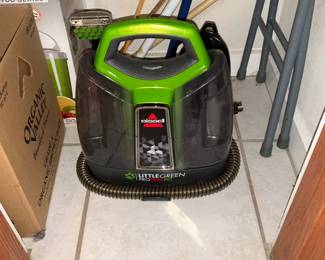 Bissell Little Green ProHeat Pet — Bissell Little Green ProHeat Pet carpet and upholstery spot cleaner shown here in green/gray. This compact extractor includes visible hose storage and clear tanks for solution and recovery; it's designed for pet stains and small-area cleaning. Unit shows light cosmetic wear from storage but no obvious cracks to tanks or major damage visible in photos; power cord and accessories appear present though not fully photographed. Measures approximately 16 inches tall x 12 inches wide x 14 inches deep and is a practical choice for spot-cleaning carpets, stairs and upholstery.