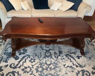 Carved Mahogany Coffee Table — Solid carved mahogany coffee table with a scrolled rectangular top and decorative pedestal base. The top shows light surface wear and a few small scratches consistent with normal use; base carving remains crisp and sturdy. Traditional styling works well with classic or transitional living rooms and the lower stretcher adds stability. Overall solid condition and ready for use; see photos for surface blemishes.
