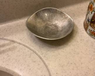 Hammered Metal Decorative Bowl — A simple hammered metal bowl with an organic, slightly squarish round profile and soft rolled edge. The surface shows an all-over hand-hammered texture and patina consistent with age and use; no maker's marks are visible in photos. Good for decorative use, keys or small serving tasks — compact and lightweight with some surface wear and minor dents as shown.