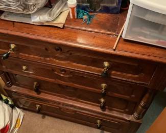 Wooden Six-Drawer Dresser — Solid-looking wooden six-drawer dresser with turned front posts, carved drawer fronts and brass drop-pull hardware. Construction appears to be medium-to-heavy solid wood or thick veneer over wood; finish is warm brown with visible wear, surface scratches and small chips along the top edge and drawer faces. Good storage capacity across three short upper drawers and three deeper lower drawers; hardware intact though aged. Estimated overall size fits a bedroom dresser footprint and it will need light cosmetic touch-up or refinishing to restore the finish.