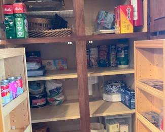 Built-In Kitchen Pantry Cabinet — Tall built-in kitchen pantry cabinet with adjustable shelving and four interior compartments finished in light maple with darker vertical divider trim. The unit shows typical light wear and scuffs from normal use, shelf peg holes visible for adjustable shelf positions, and one cabinet door removed or open in photos; hardware appears intact. Useful for pantry storage, linens, or kitchen organization; solid plywood/veneered construction estimated from visible edges. Overall condition good with cosmetic wear consistent with regular use.