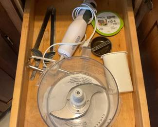 Mixed Kitchenware Lot — A large lot of everyday kitchenware including nested stainless mixing bowls, metal cake pans and molds, colanders, a few nonstick frying pans, glass lids, assorted baking tins, plastic storage lids, and small appliances/attachments (hand blender parts and food-processor bowl/blade shown). Pieces are mixed metals, glass and plastic with visible wear and light staining on some cookware; overall serviceable for home use or as backup pieces. No major brand markings visible in photos; items sold as-is and sold together as one lot. Estimated combined size and weight below reflect the full grouped contents.