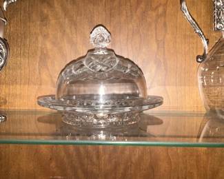 Pressed Glass Covered Butter Dish — Attractive pressed glass covered butter dish with a domed lid and decorative knob perfect for display or tabletop use. The clear molded-glass set includes a shallow plate with a raised center and a dome lid featuring a faceted knob and molded border pattern. Overall dimensions are modest, making it easy to store or display in a china cabinet. The piece is in good condition with no visible chips or cracks from the provided photos but may show light surface scratches consistent with normal use.