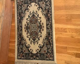 Small Oriental Wool-Blend Runner Rug — Small Oriental-style runner with a classic medallion and floral border in cream, navy and brown tones. Low-pile wool-blend construction with knotted fringe on both ends and a tightly woven edge. Measures approximately 24 in wide and 42 in long, a handy size for hallways or beside a bed; lightweight and easy to move. Rug is in good condition with light wear to the fringe and minimal surface soiling consistent with normal use.