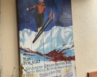 Winter Park Ski Wall Plaque — Painted wooden wall plaque advertising "WINTER PARK" skiing with vintage-style artwork of a skier, mountains and text including "SKI LESSONS" and "RENTALS." The piece is painted on vertical plank wood with intentional distressed finish for a rustic look and would suit ski-lodge or mountain-themed decor. Condition is good with light surface wear and slight paint distress consistent with age and display; no major damage visible. Overall narrow, tall profile makes it easy to hang above furniture or in an entryway.