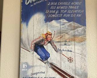 Ski Breckenridge Wood Wall Art — Wood plank wall art printed with a retro skier and bold "Ski Breckenridge" lettering, distressed finish, and promotional text listing ski area stats. The piece is lightweight painted wood with visible vertical plank seams and intentionally worn/distressed surface for vintage appeal. Good decorative condition with surface wear and paint distressing consistent with the design; hanging hardware not visible. Measures roughly 36 x 18 inches and makes a seasonal or mountain-lodge accent piece.