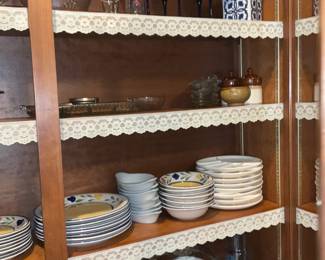 Oak China Cabinet with Glass Doors — Solid oak china cabinet with glass-paneled doors and adjustable shelving shown with lace shelf trim. The cabinet features brass hardware, plated shelf standards for adjustable heights and a warm medium oak finish; doors close with visible round ceramic knobs. Good solid condition with light surface wear and small scuffs consistent with normal use; glass panels intact. Overall practical storage for dinnerware or display, measures approximately as shown below.