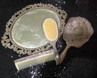 This is a vintage silver-plated four-piece vanity and dresser set.