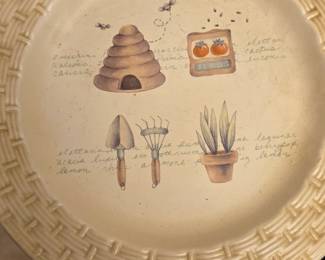This is a Sonoma ceramic dinner plate featuring a garden and beehive motif.