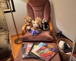 Mauve Upholstered Wood-Framed Lounge Chair with Matching Ottoman, Brass Floor Lamp, Plush Stuffed Animals and Children’s Books