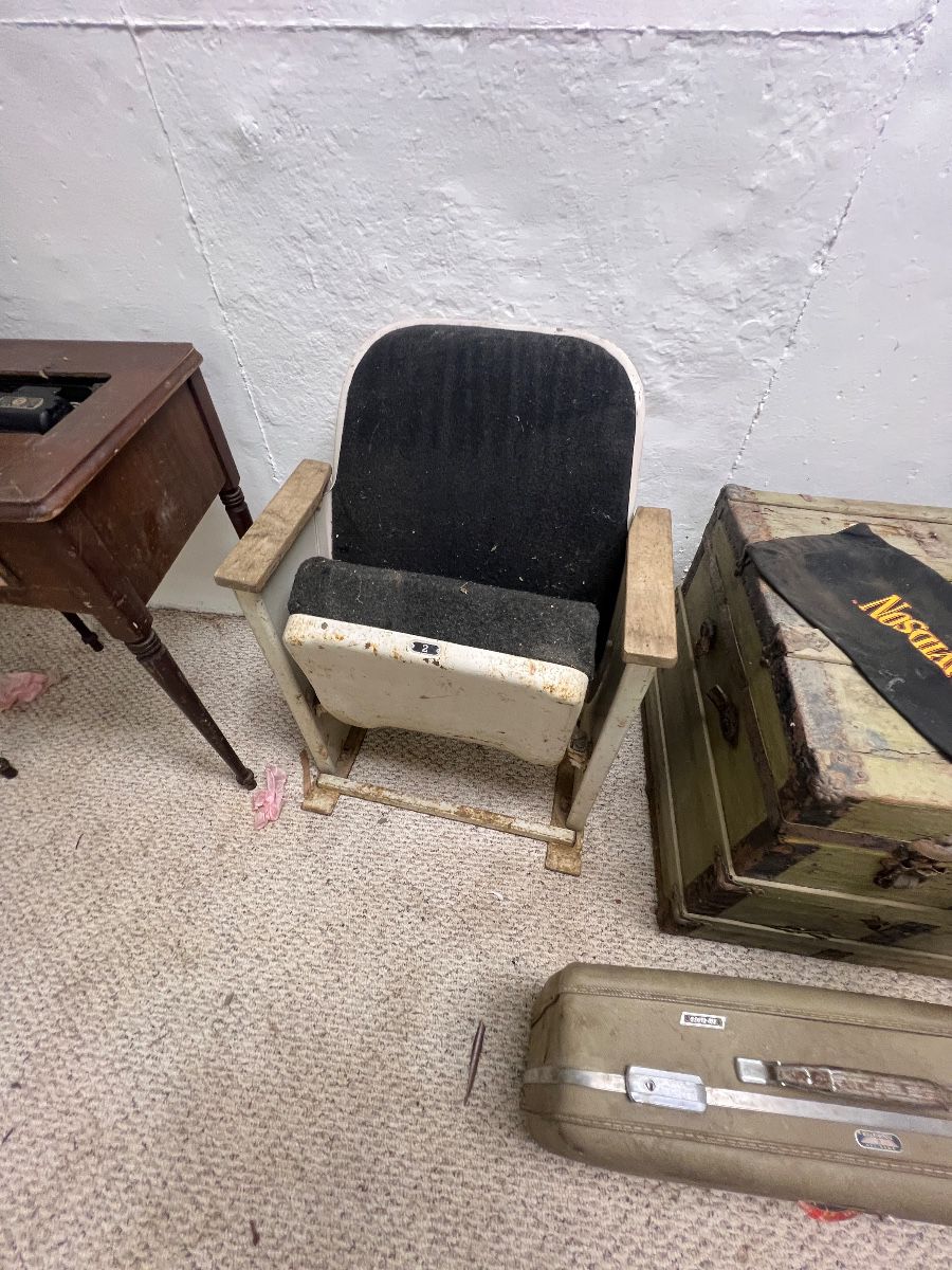 vintage single movie theater or auditorium seat featuring black upholstered padding, wooden armrests, and a tip-up seat mechanism