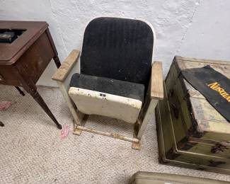 vintage single movie theater or auditorium seat featuring black upholstered padding, wooden armrests, and a tip-up seat mechanism