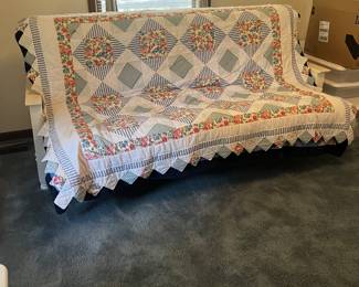 Pretty quilt on top of the white wood futon style sofa that flattens to a double bed.