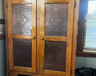 Antique wooden pie safe featuring punched tin door panels and a top storage drawer.