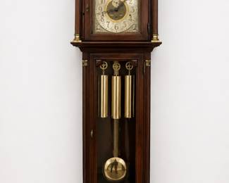 traditional wooden grandfather clock featuring an ornate carved pediment and a polished brass pendulum.