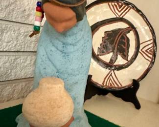 Southwestern-style figurine of a kneeling woman, Southwestern-style polychrome ceramic pottery plate possibly inspired by Hopi, Zuni, or Acoma Pueblo traditions.