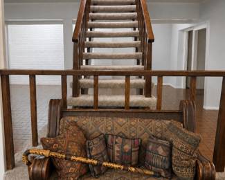 Antique wooden settee with southwestern-style tapestry upholstery and a vintage walking stick