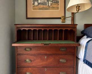 Mahogany drop-front secretary desk featuring a green leather writing surface and classic brass drawer pulls. .