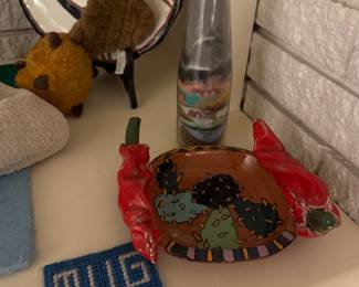 Southwestern-style clay dish featuring a hand-painted cactus motif on the base and sculptural red chili peppers attached as handles on the sides, Mug Rug, vintage art bottle with a layered southwestern desert landscape scene