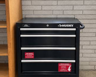 Husky tool chest in garage that is packed with tools and yard equipment