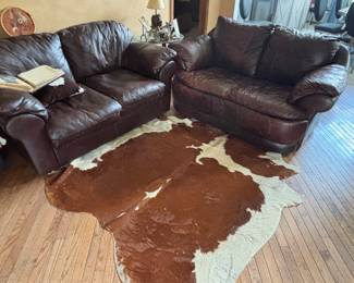 Cow hide rug. Two leather love seats 
