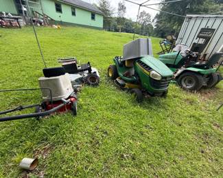 Group of John Deere and Sabre riding lawn tractors, push mower, and mower parts/accessories