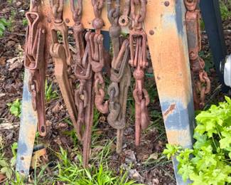 Assorted heavy-duty chains, hooks, binders, and steel rigging/implement components