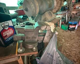 Vintage cast-iron bench vise with attached abrasive/wire-wheel grinder assembly