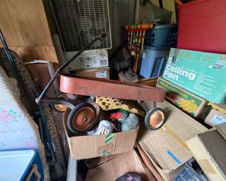 Mixed storage-unit contents with vintage-style pull wagon, croquet set, tools, small appliances, furnishings, and boxed household goods