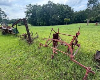 Group of early horse-drawn farm implements, including riding cultivator and sickle-bar mower