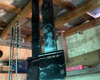 Pair of heavy-duty black metal strap hinges with hanging long auger bits nearby